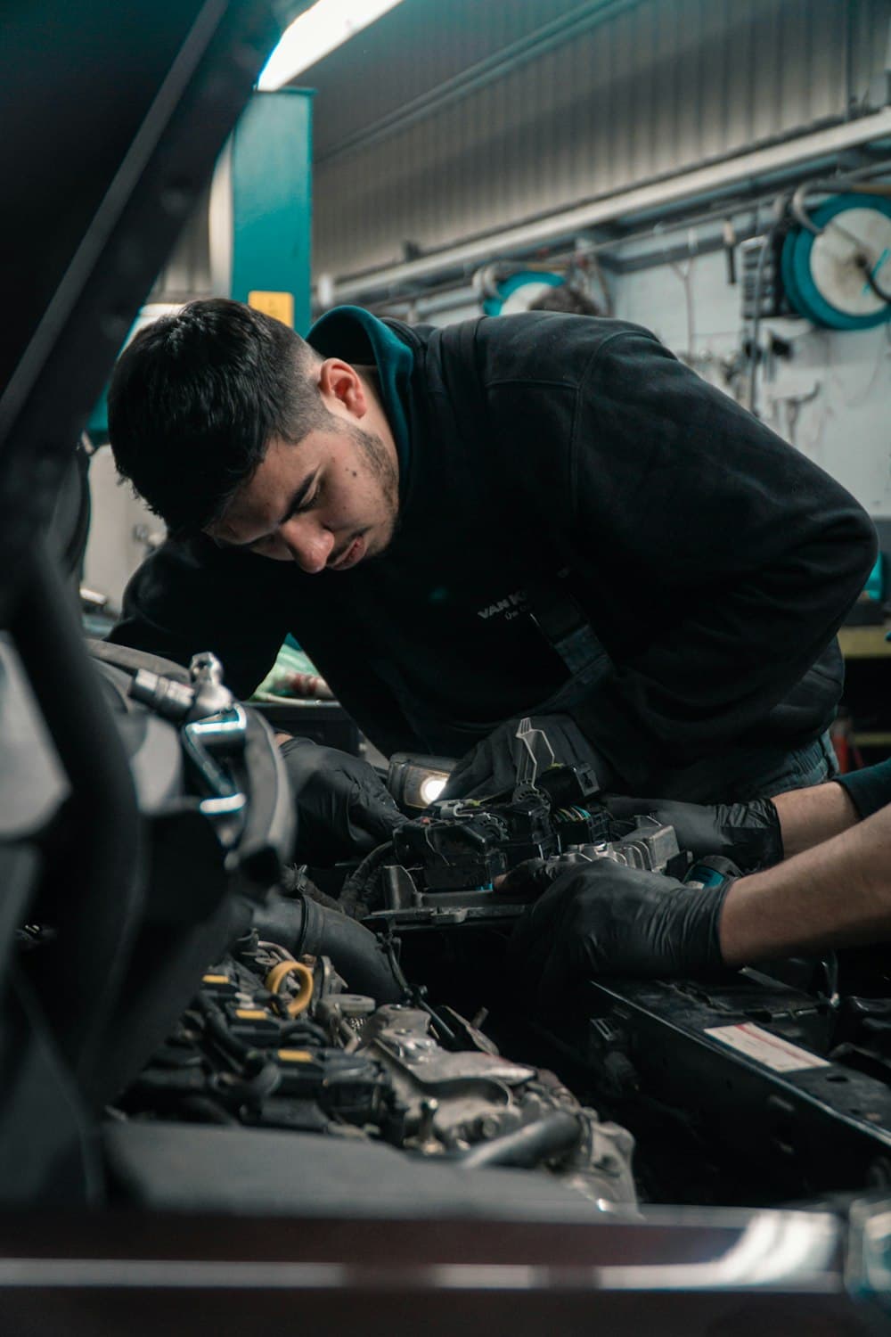 Mechanic working under the hood of a car in a repair shop